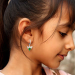 A person wearing green angelica silver dangling hoop earrings with a butterfly design.