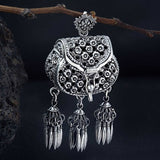 A sterling silver pendant in the shape of a handbag with an oxidized finish, featuring intricate details and hanging from a chain.