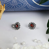 Beautiful flower inspired Stud earrings for women. Crafted in sterling silver finished in oxidised, these earrings are embellisehed with Red color zirconia in the centre and Marcasite all around.